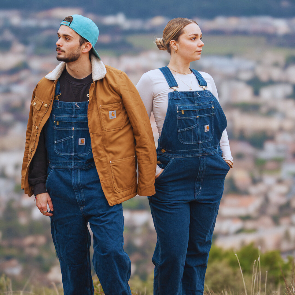 Deux personnes en salopette Carhartt Denim sur une colline au-dessus de la ville
