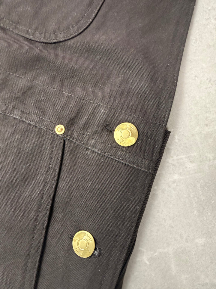 Salopette Carhartt Canvas marron : boutons de côté en laiton à la patine irrégulière, avec de petites marques en surface