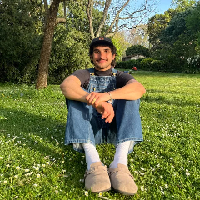 Homme assis dans l’herbe en salopette Carhartt Denim, largeur de jambe visible