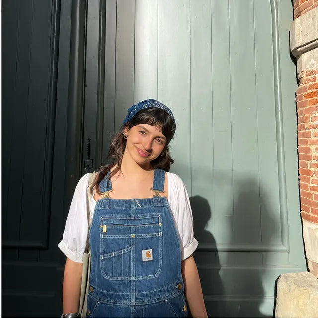 Gros plan sur la bavette portée : poche poitrine, étiquette Carhartt et boucles des bretelles