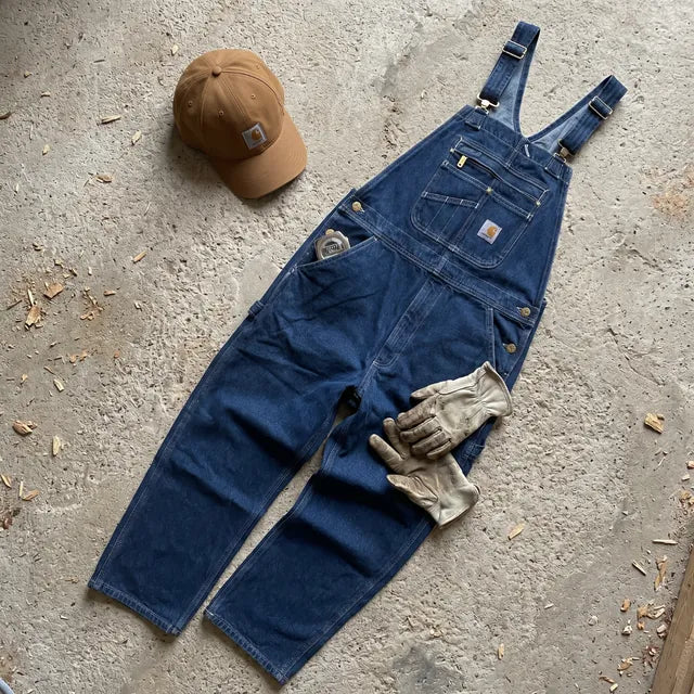 Salopette Carhartt Denim posée à plat avec une casquette Carhartt marron