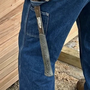 Marteau glissé dans la boucle porte-marteau, poche à outils sur la jambe