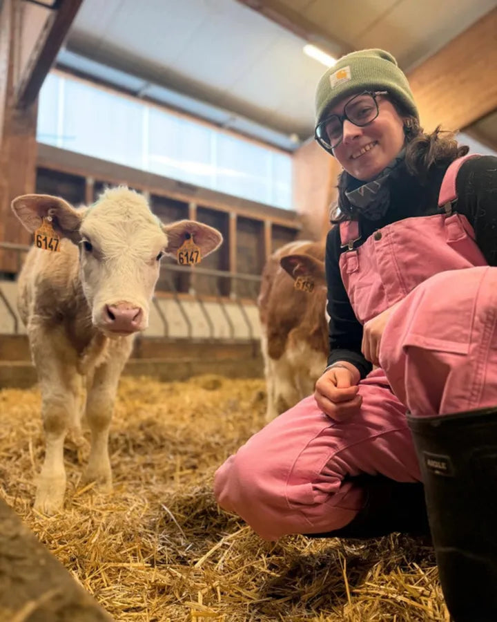 Cliente en salopette rose à la ferme, auprès des veaux
